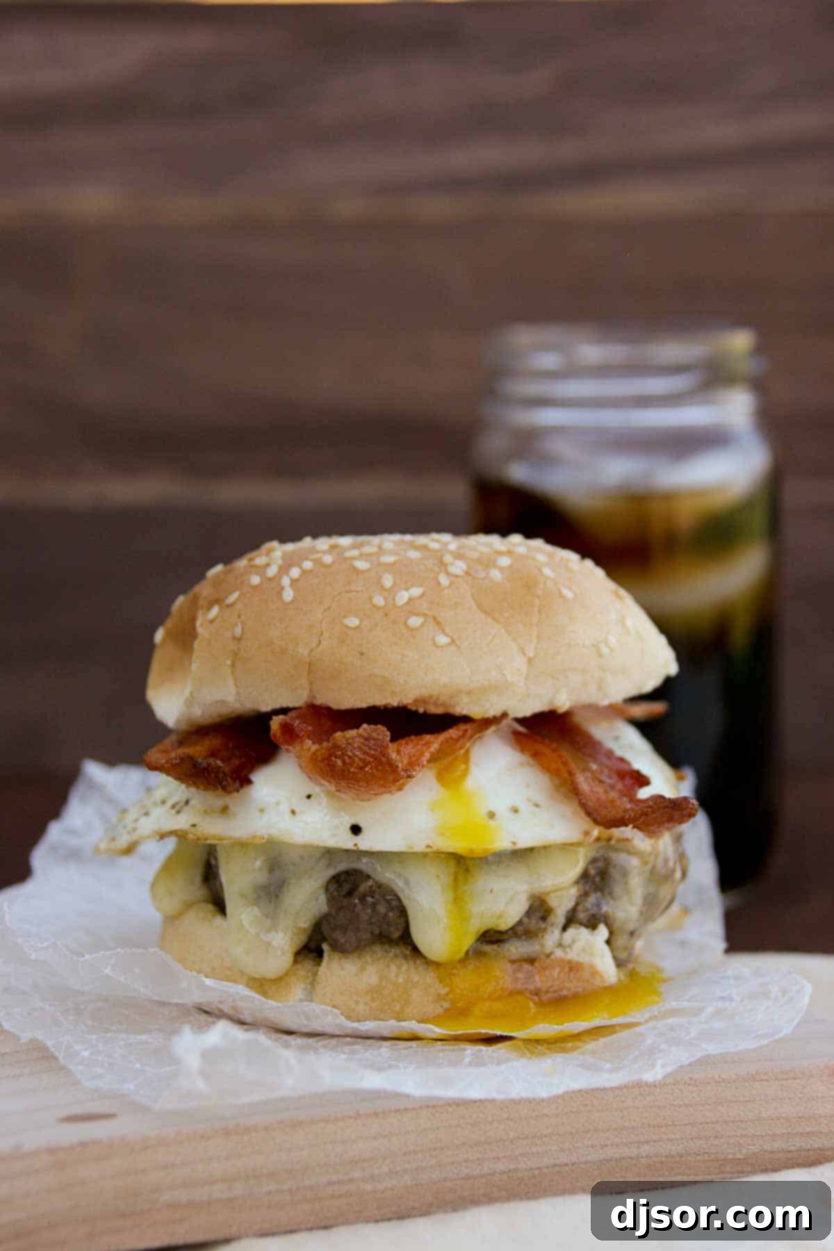 Bacon and Egg Burger on a cutting board, topped with a fried egg and crispy bacon