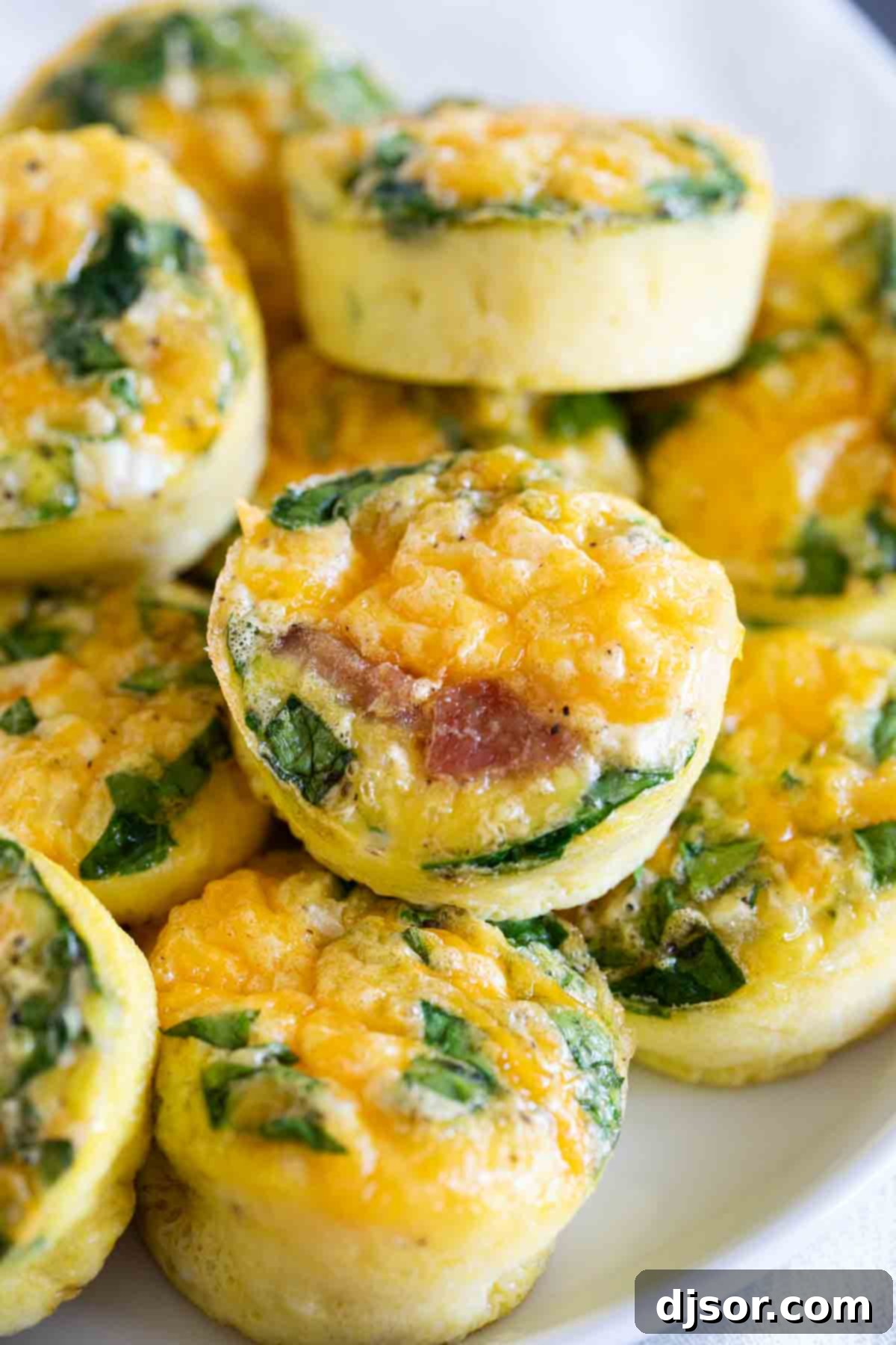 A great make ahead or breakfast on the go, these Egg Muffins and super simple, and super versatile! A close-up shot of freshly baked Egg Muffins featuring spinach, ham, and cheese, showcasing their appetizing appearance and texture.