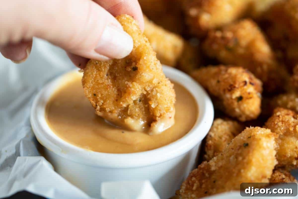 Enjoying a golden chicken nugget perfectly coated in the irresistible homemade Chick-fil-A sauce. Dipping a crispy chicken nugget into rich homemade chick fil a sauce
