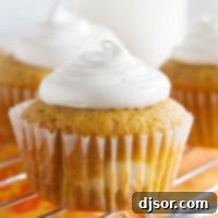Pumpkin Cheesecake Cupcakes on a cooling rack over an orange cloth.