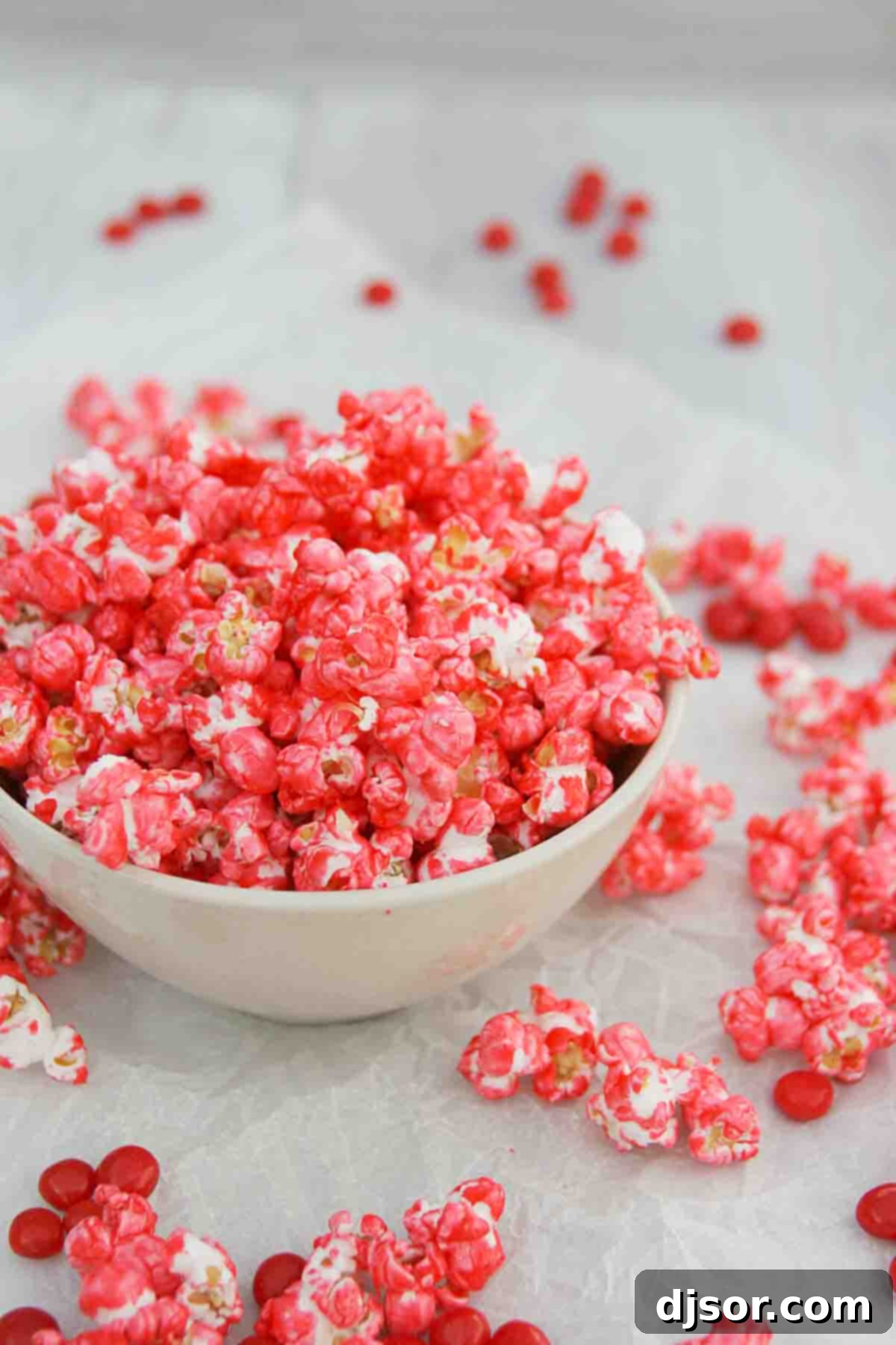Red Hot Popcorn - spice up your popcorn with this easy cinnamon coated popcorn. bowl filled with Red Hot Popcorn with red hot candies around
