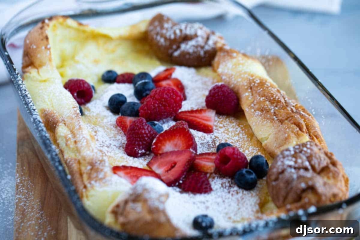 Dutch Baby (or German Pancake) topped with an abundance of fresh berries and a light dusting of powdered sugar, presented beautifully for breakfast