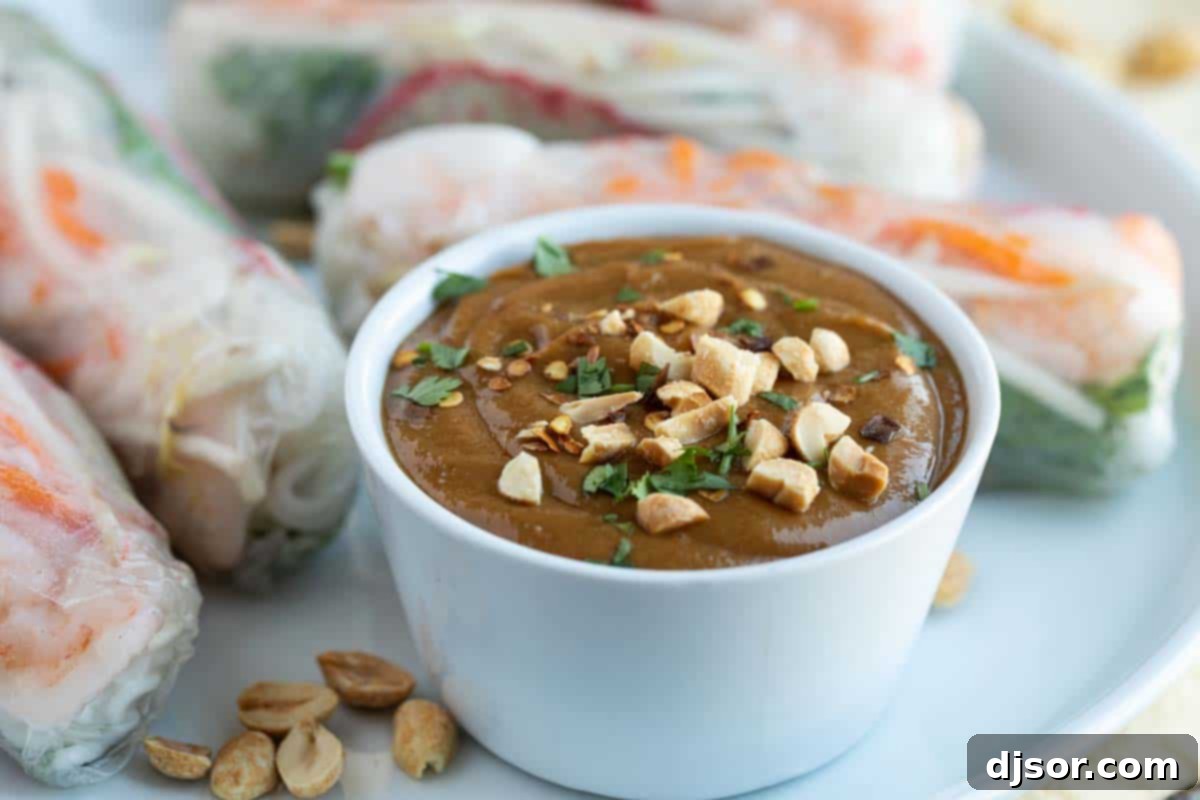 A beautifully plated dish featuring spring rolls arranged around a bowl of creamy homemade peanut sauce, inviting you to dip in.