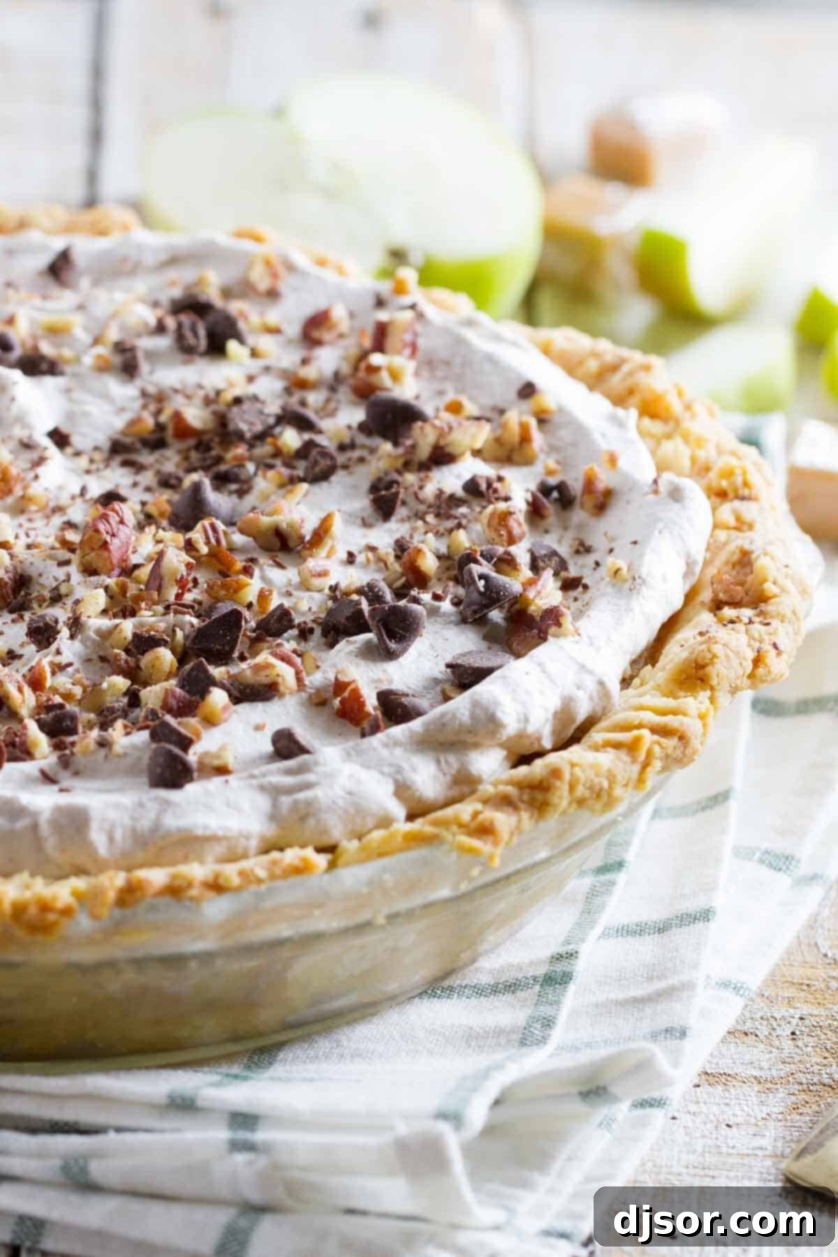 Taffy Apple Pie with a Cheesecake Twist 3 A close-up shot of the Taffy Apple Cheesecake Pie, highlighting its decadent topping of melted chocolate and crunchy nuts. The golden-brown crust and creamy filling are visible beneath, showcasing the rich textures of this unique dessert.