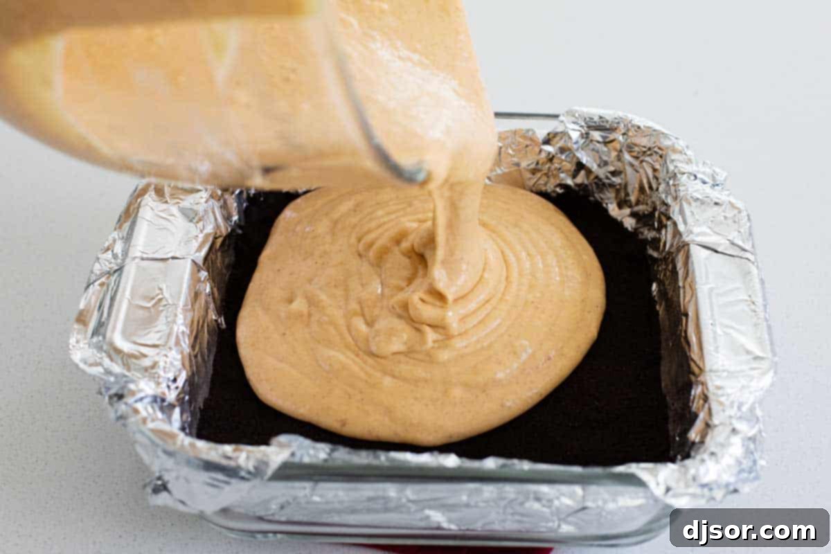pouring cheesecake batter over a chocolate cookie crust