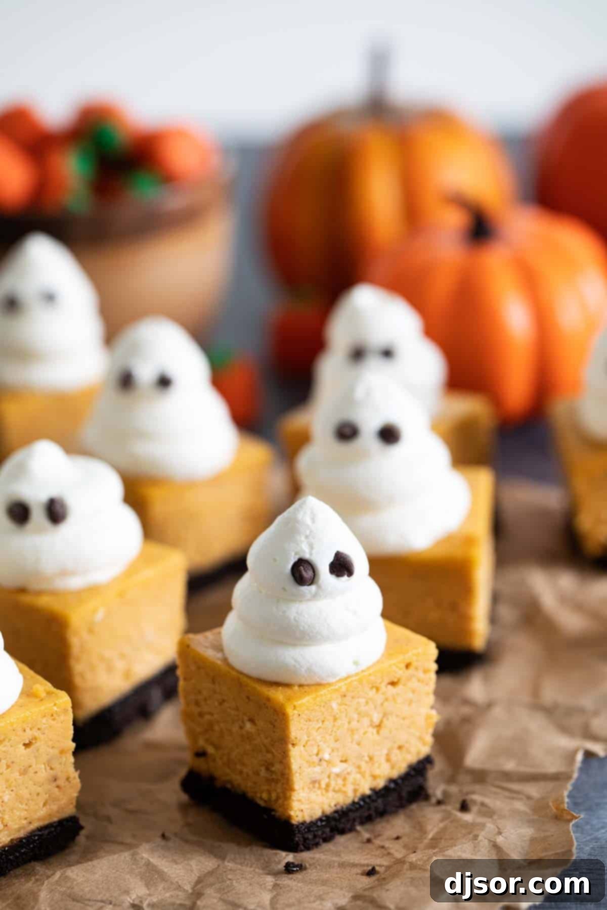 Pumpkin cheesecake bars topped with whipped cream ghosts.