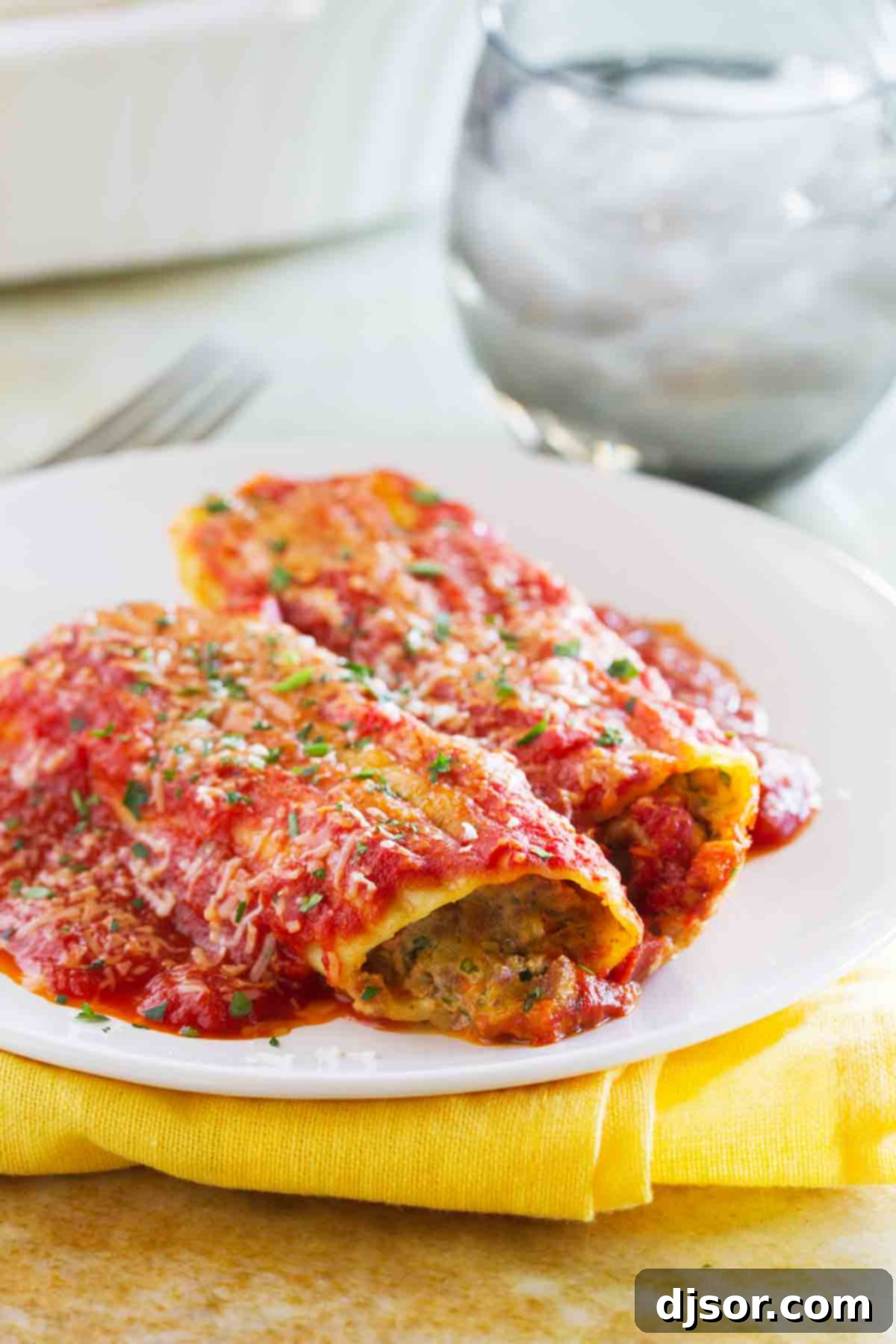 A serving of Stuffed Manicotti with Beef on a plate, garnished with fresh herbs.