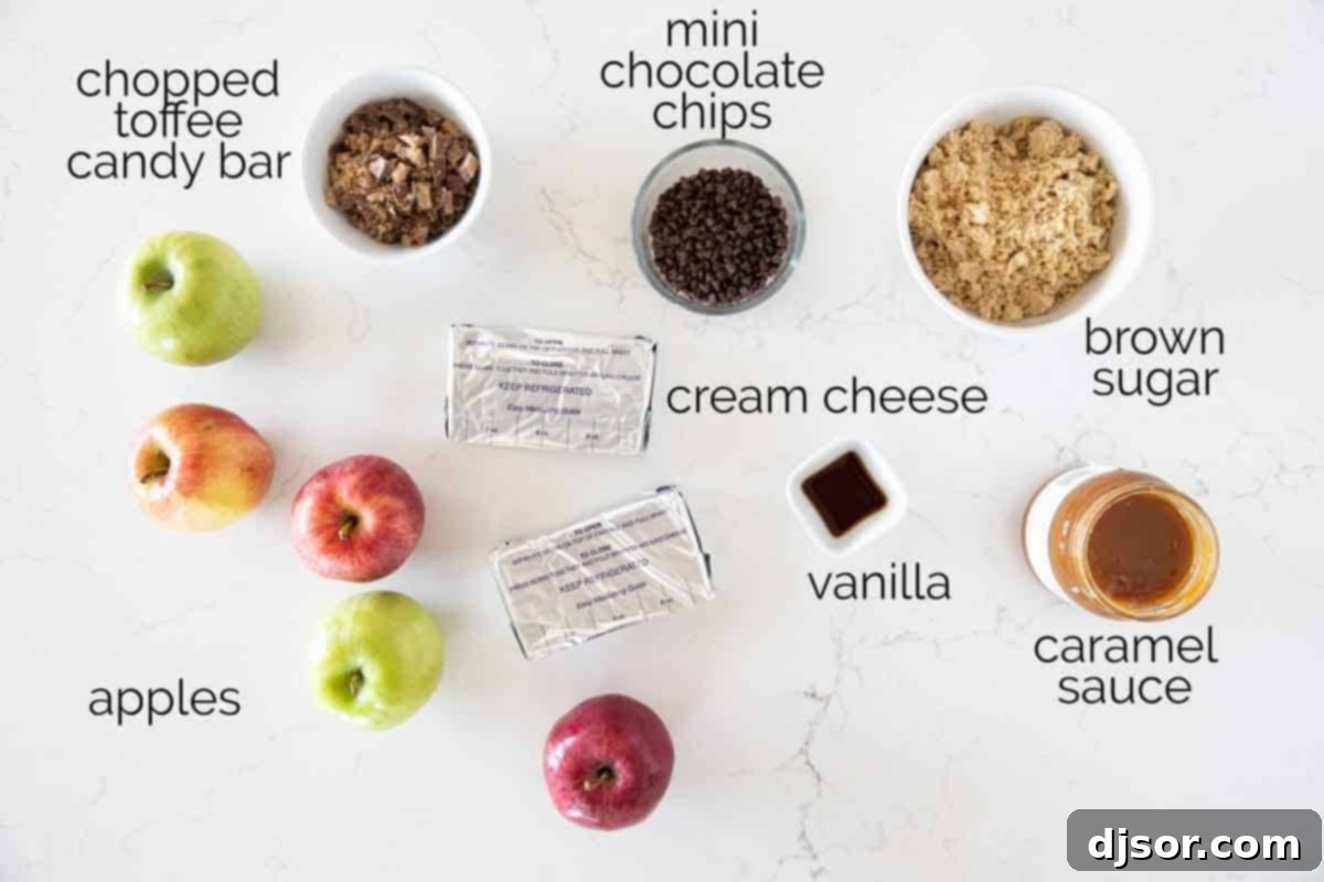All the delicious ingredients laid out for making caramel apple dip: cream cheese, brown sugar, vanilla extract, mini chocolate chips, caramel topping, Heath bars, and fresh apples.