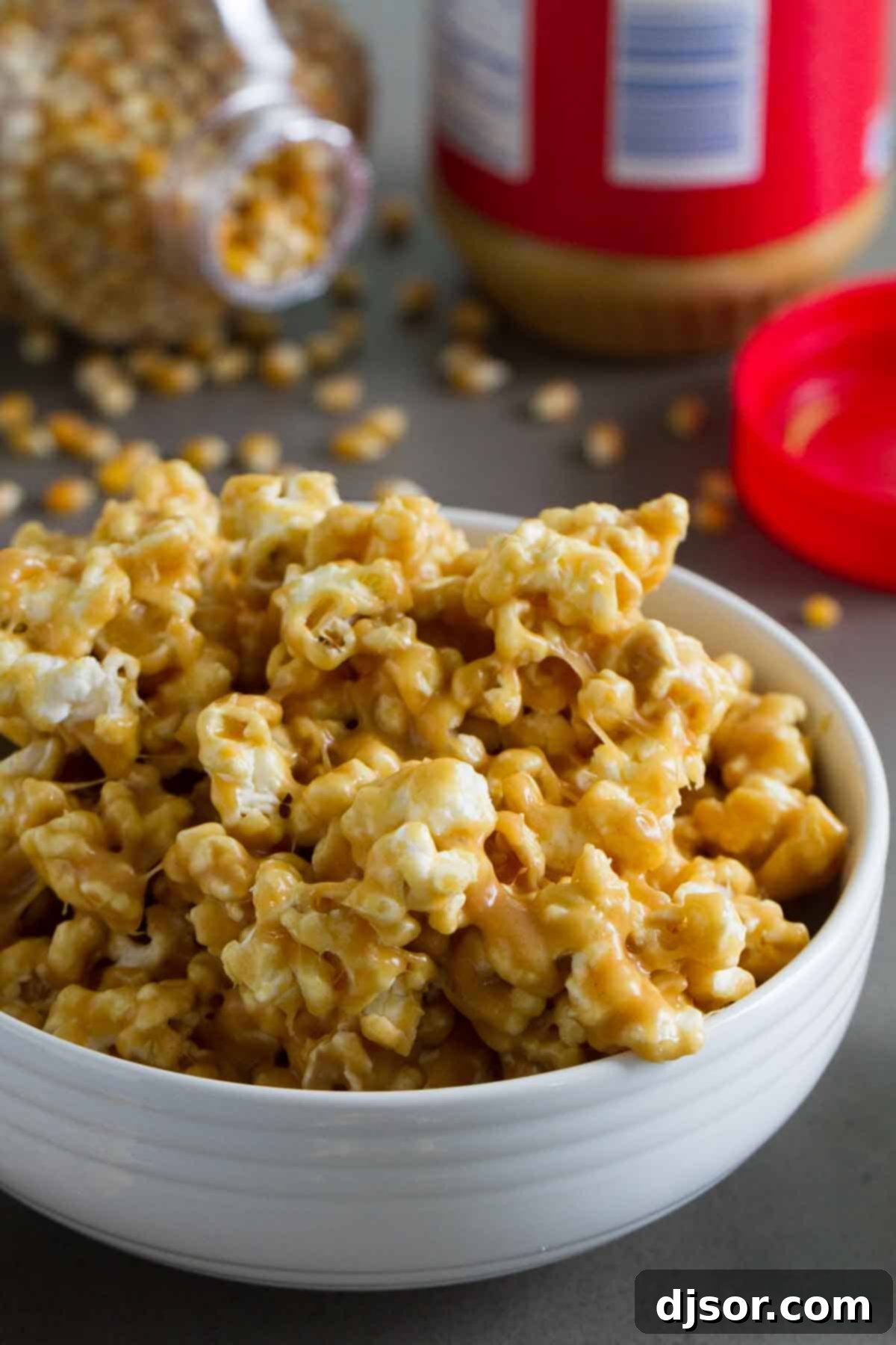 Peanut butter lovers won’t be able to stay away from this Peanut Butter Popcorn - popcorn that is coated with a sweet and sticky peanut butter coating. A large bowl brimming with freshly made Peanut Butter Popcorn, with more popcorn visible in the soft-focus background, highlighting its irresistible texture.