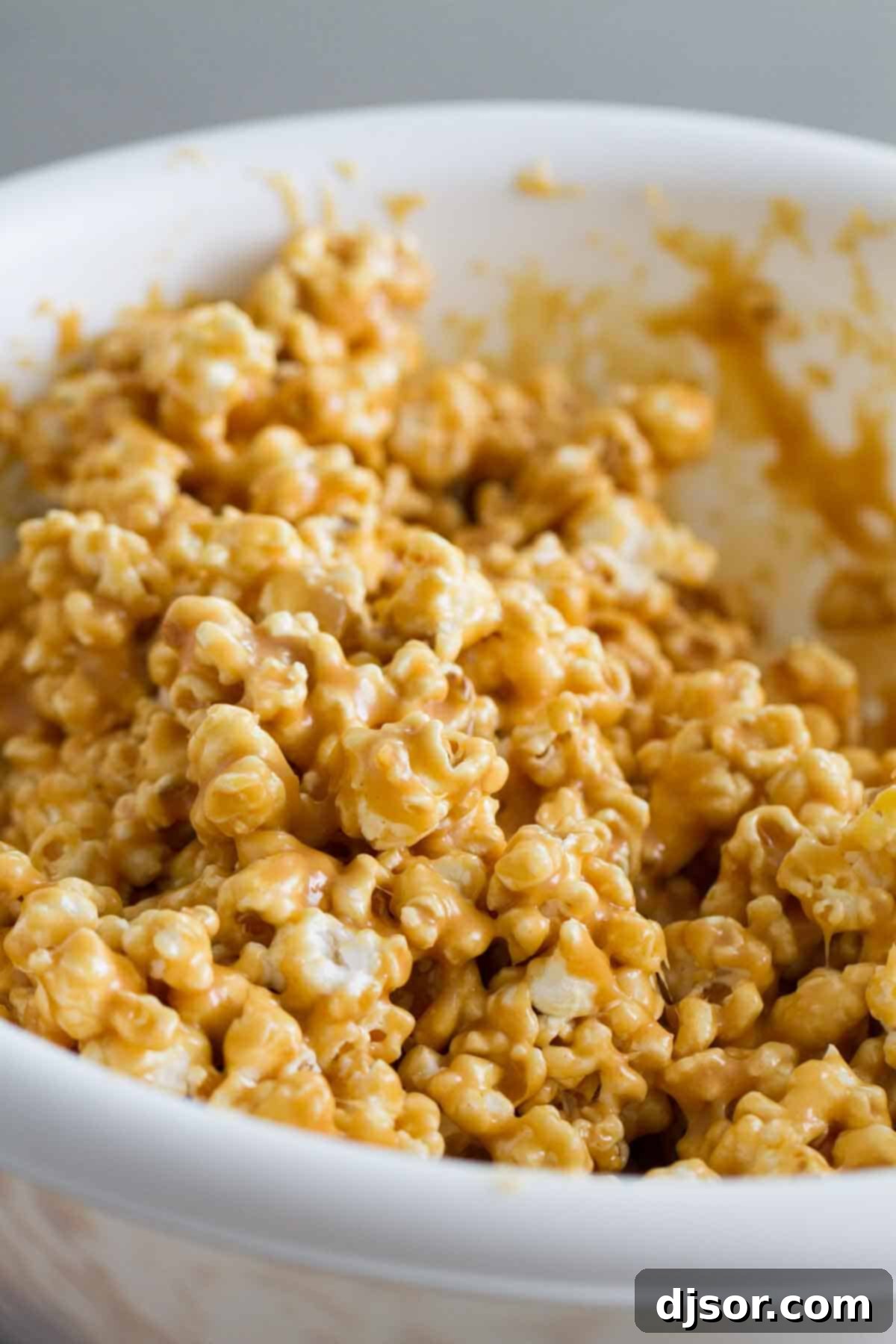 Peanut butter lovers won’t be able to stay away from this Peanut Butter Popcorn - popcorn that is coated with a sweet and sticky peanut butter coating. A large, rustic bowl filled to the brim with golden, sticky Peanut Butter Popcorn, ready for sharing and indulging.