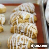 Harvest Pumpkin Scones 2 Pumpkin scones with icing on a baking sheet.