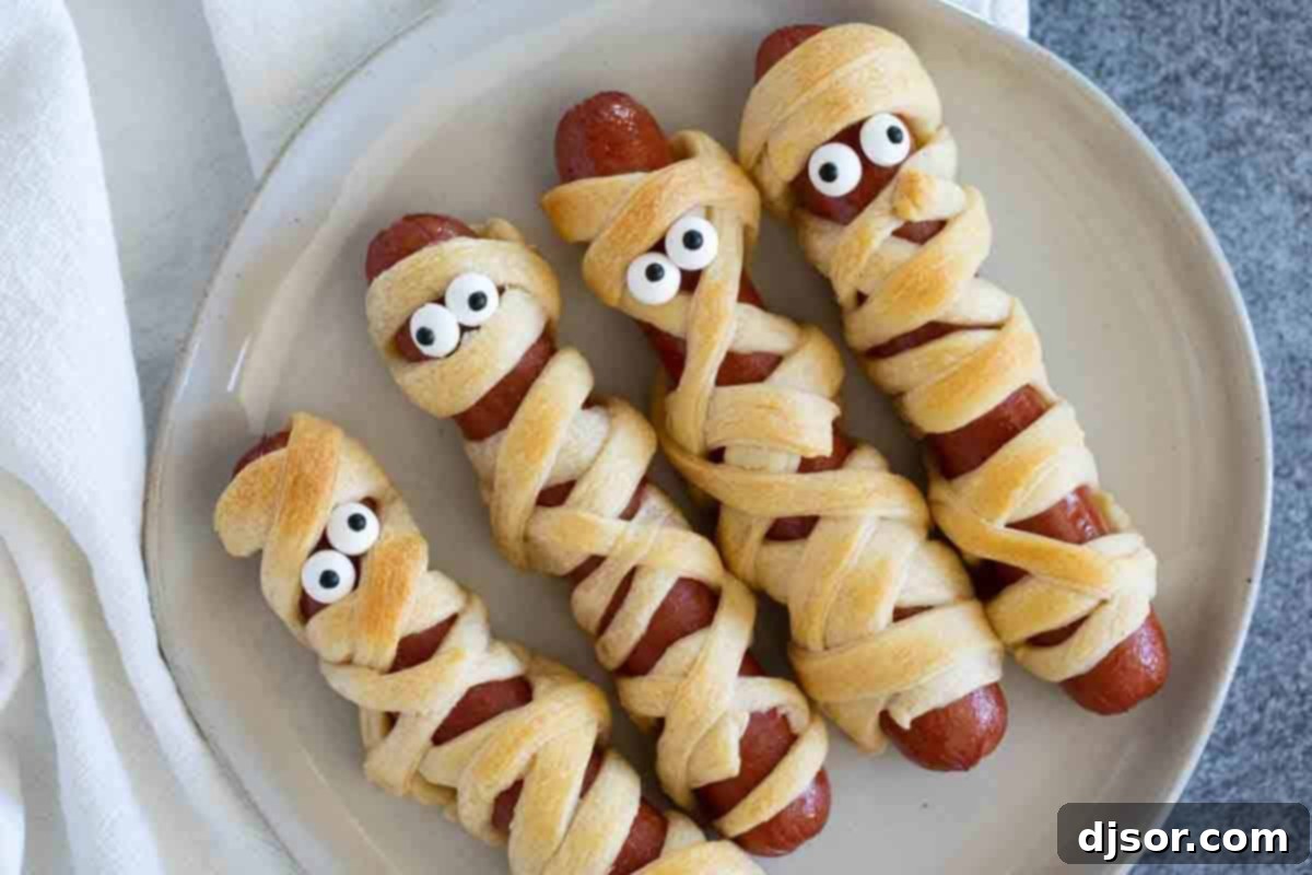 Perfect for Halloween or for a spooky dinner or lunch, these Mummy Hot Dogs are kid approved and couldn’t be easier! Four Mummy Hot Dogs on a plate, ready to be enjoyed.