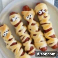 Bandaged Bites 2 Mummy hot dogs with candy eyes on a plate.