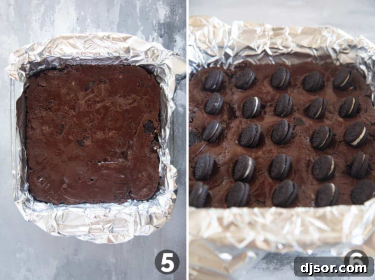 Ultimate Oreo Fudge Delight 5 Fudge being pressed into a baking dish and topped with whole mini Oreos, ready for chilling.
