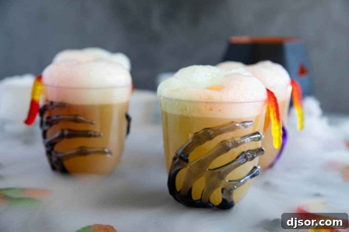 Spooky Witches Brew for Halloween Glasses with skeleton hands holding a vibrant green Witches Brew, a non-alcoholic drink with frothy sherbet, perfect for Halloween parties.