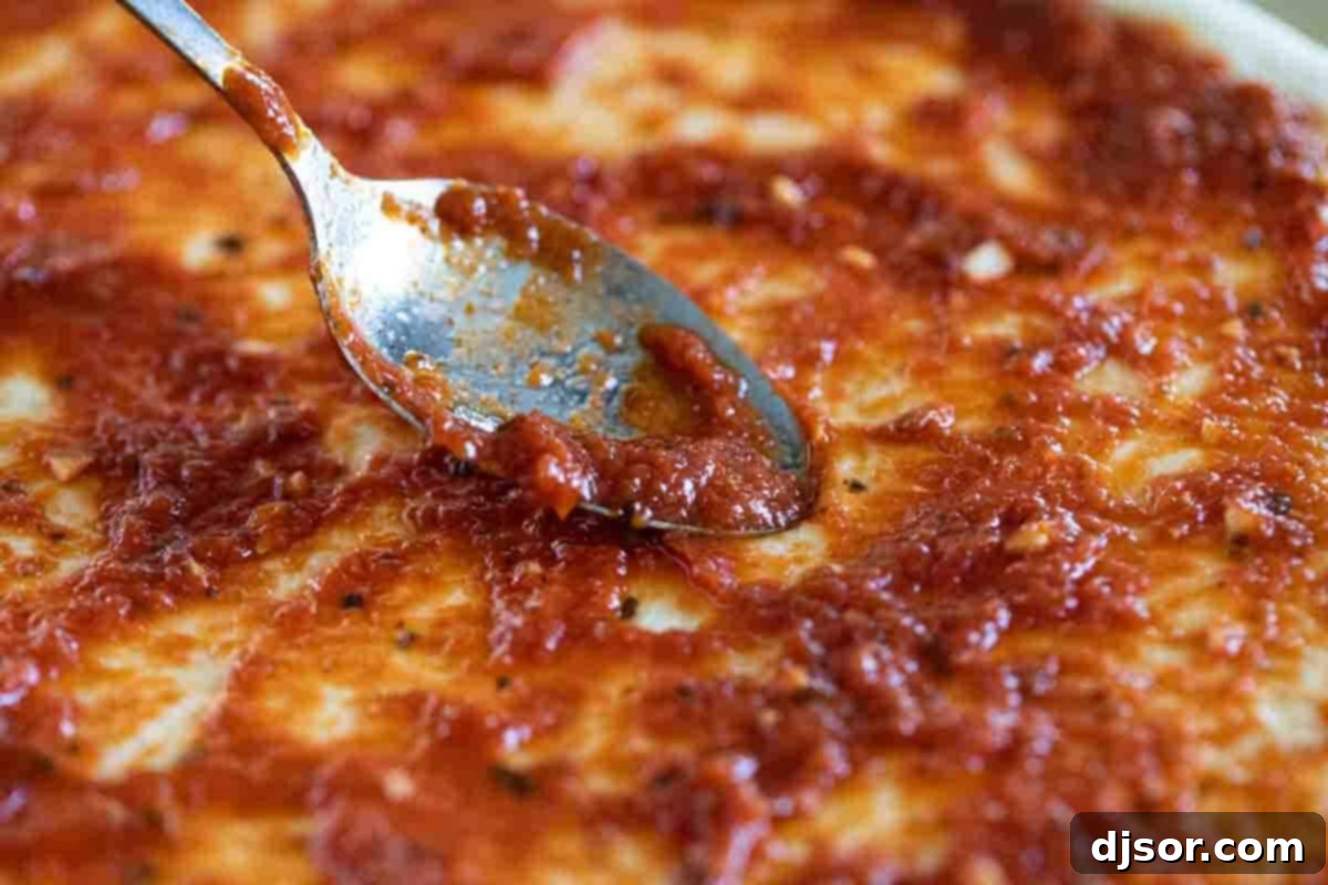 Smoothly spreading the homemade pizza sauce onto a pizza crust. Spreading pizza sauce with a spoon.