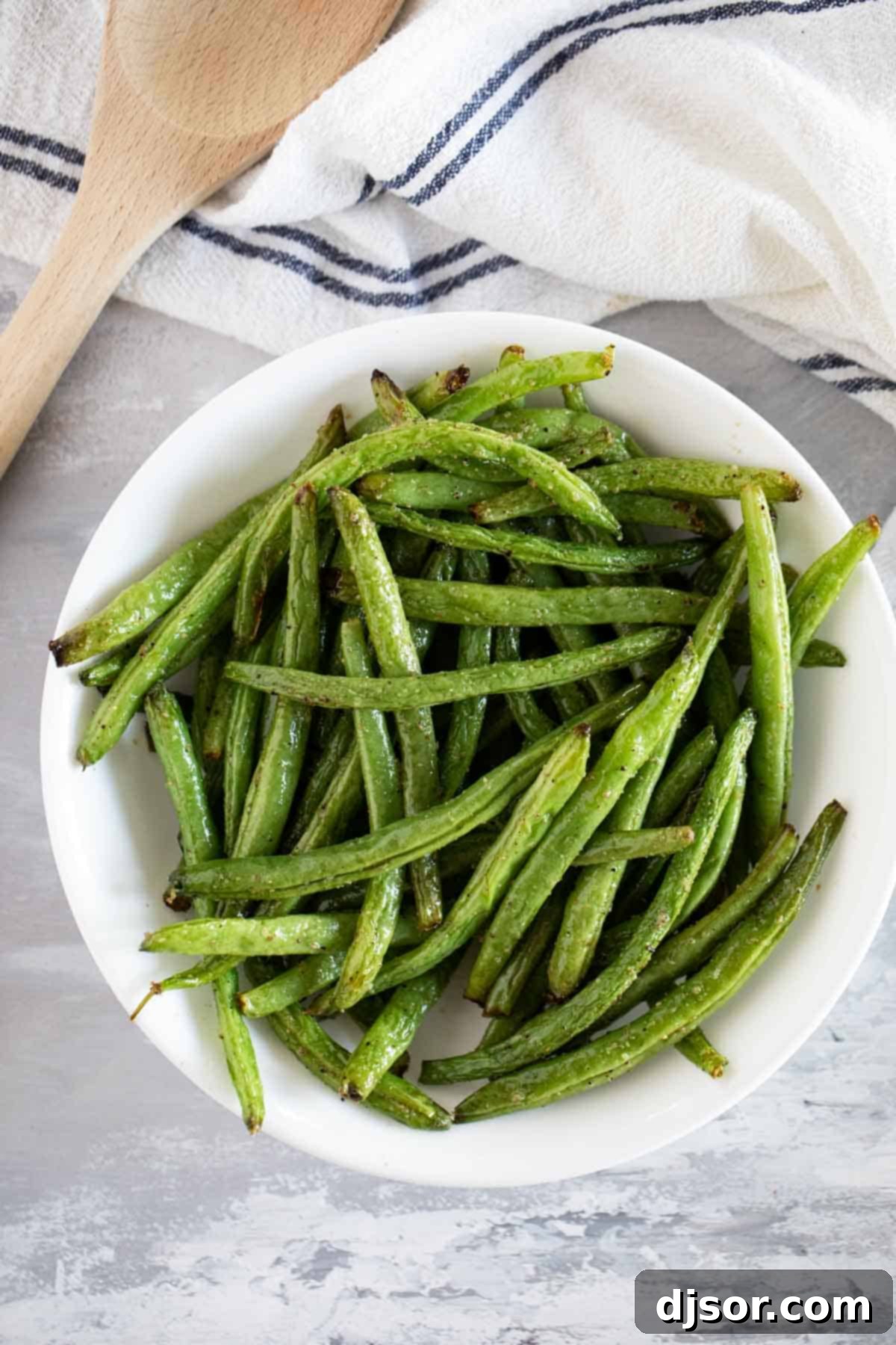 Delicious Air Fryer Green Beans ready to serve. A close-up shot of a serving bowl filled with golden-brown, perfectly air-fried green beans, garnished and ready to eat.