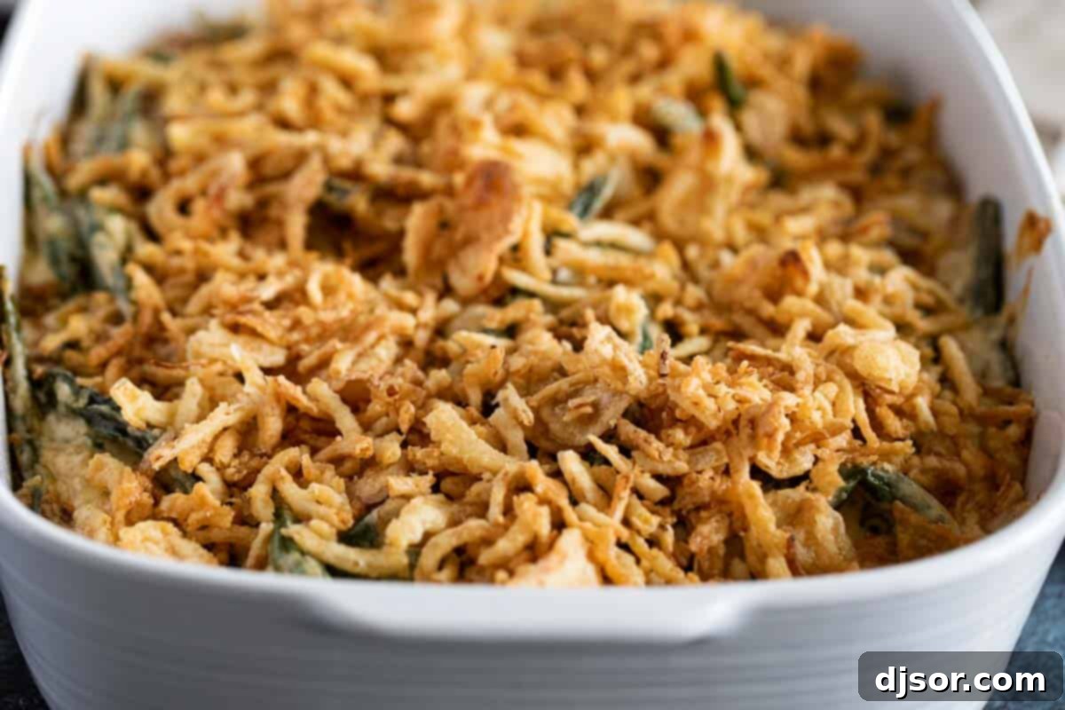 A rectangular baking dish filled with homemade green bean casserole, golden brown and bubbling, crowned with a generous layer of perfectly crispy fried onions.