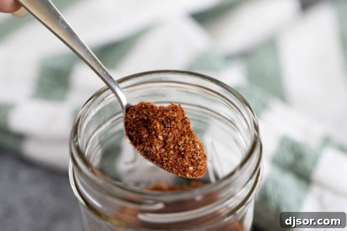 A close-up of a spoon piled high with the aromatic homemade taco seasoning. A spoon overflowing with homemade taco seasoning against a blurred background.