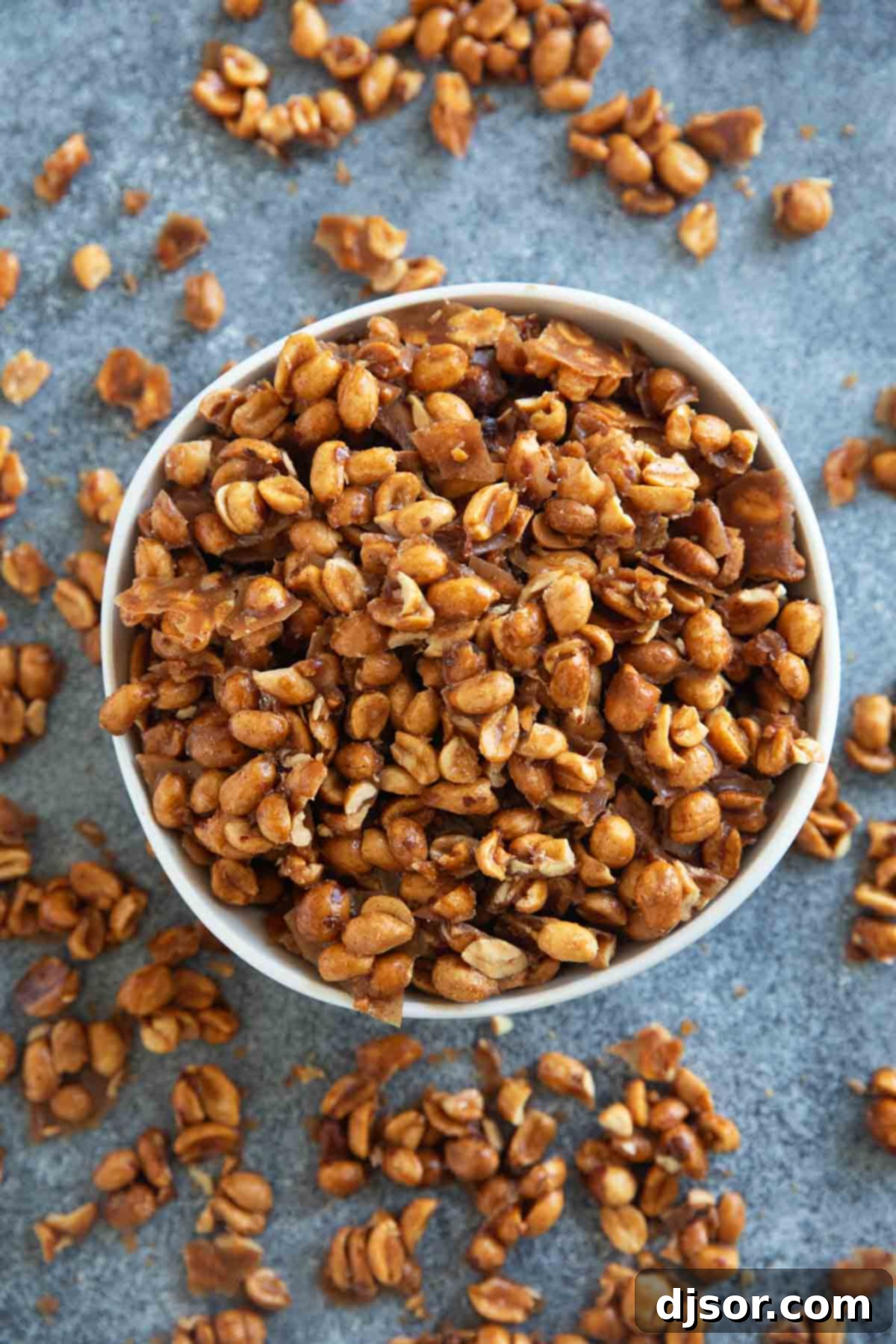 Bowl overflowing with golden-brown, crunchy Toffee Peanuts, ready to be enjoyed.