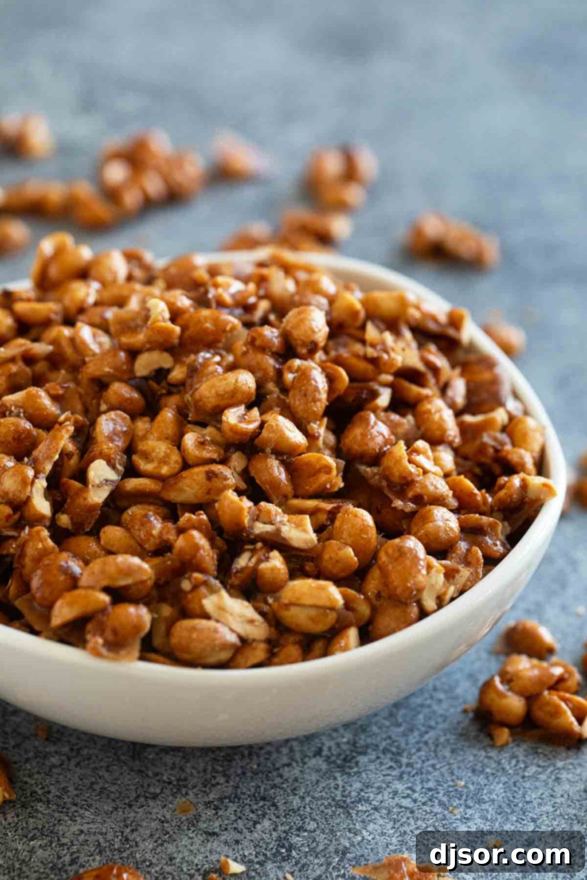 White bowl filled with golden Toffee Peanuts, showcasing their glossy texture and inviting appearance.