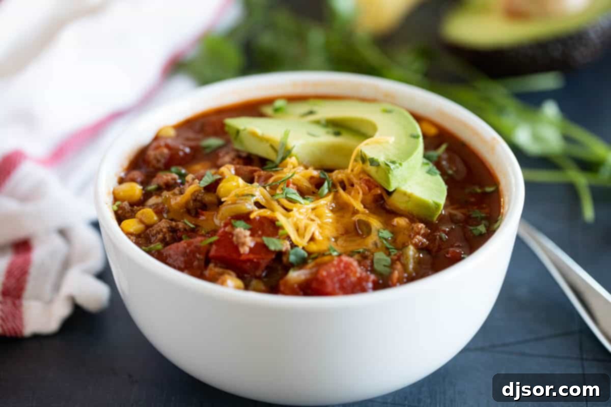 Heartwarming Taco Soup topped with fresh cheese and creamy avocado slices. Bowl of taco soup topped with cheese and avocados, a perfect comfort food.