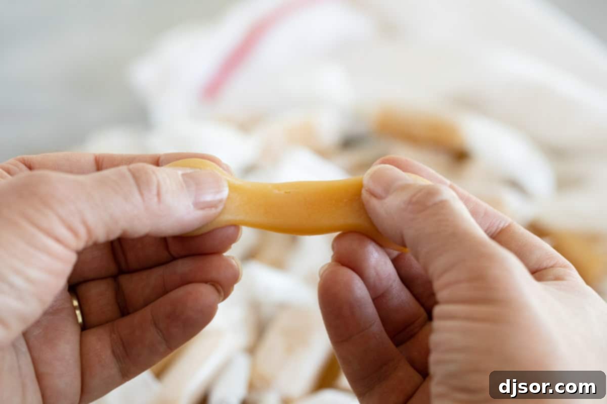 Perfect every time, these microwave caramels couldn’t get much easier! A few minutes of hands on time and you have caramel candy that tastes like you bought it at a fancy candy store. Caramel being stretched apart by two hands.