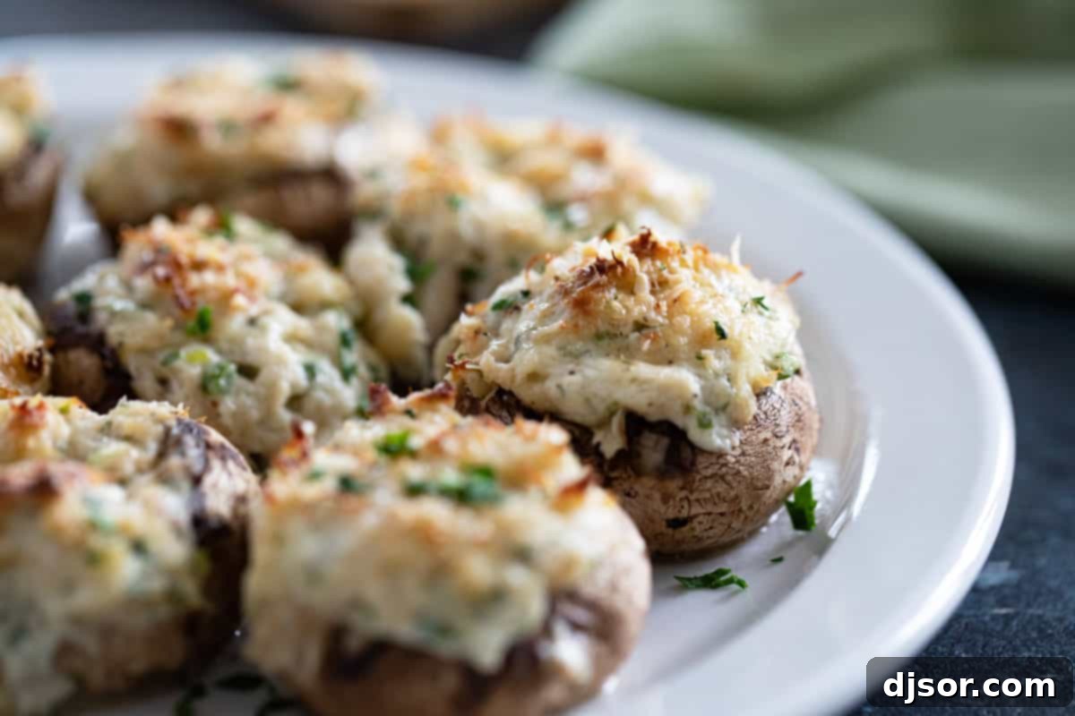 Delectable Crab Stuffed Mushrooms, perfectly baked with golden-brown cheese and fresh parsley garnish, served on a pristine white plate.