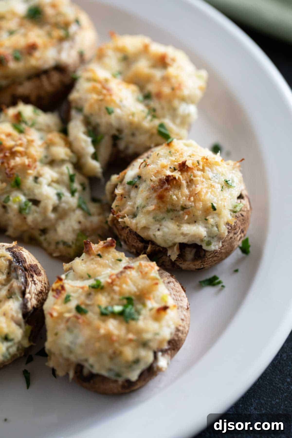 Beautifully plated Crab Stuffed Mushrooms, generously sprinkled with fresh parsley for a vibrant finish, ready to be served.