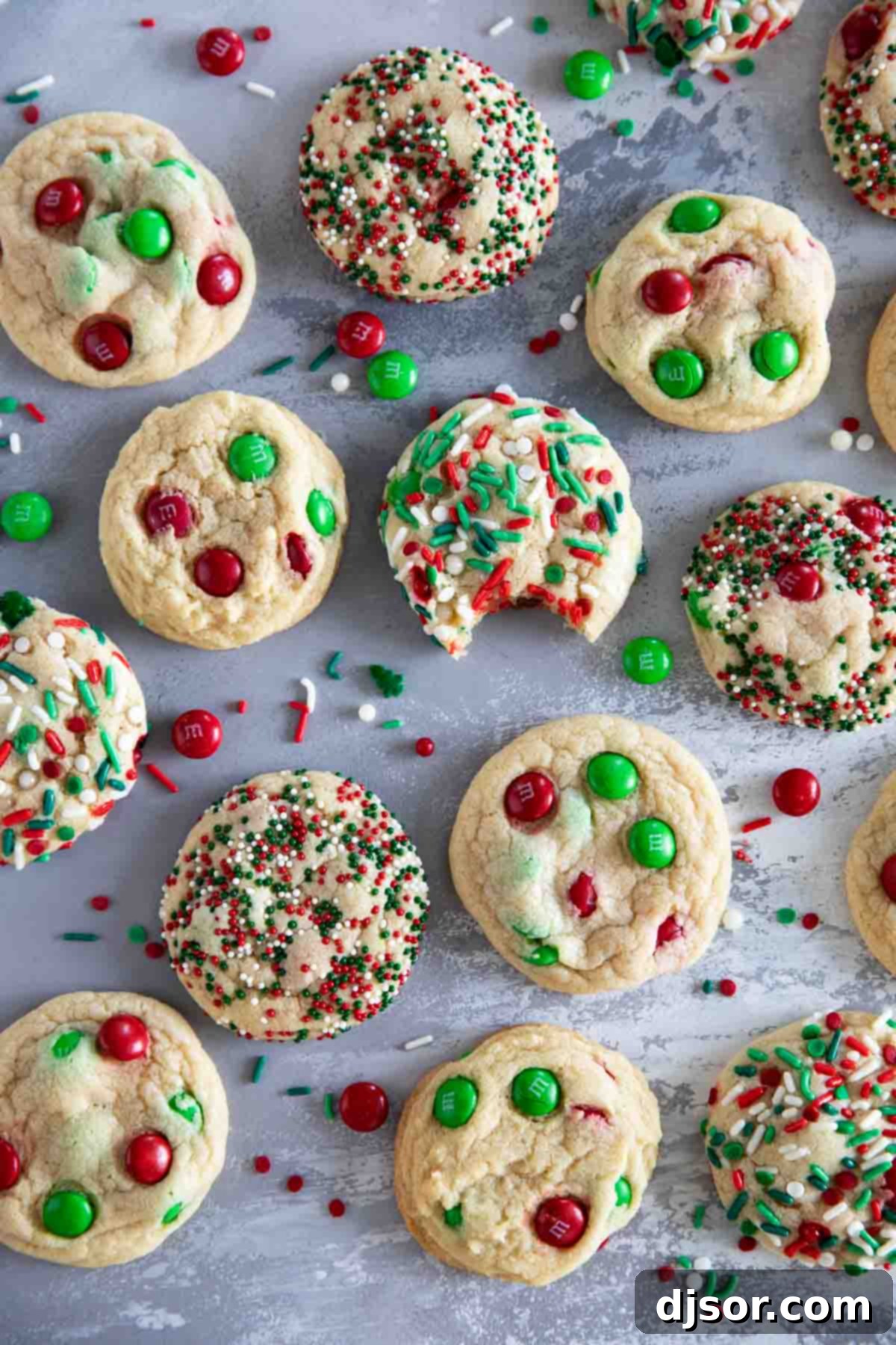 Soft, delicious, and super festive, these Christmas M&M Cookies will be a favorite for both kids and adults. Add sprinkles to make them even more fun! A freshly baked Christmas M&M Cookie with a bite taken out, revealing its soft and chewy interior, resting on a festive surface.