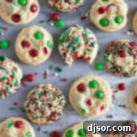 Colorful M&M Christmas Cookies 2 Christmas M&M Cookies on a surface with a bite taken out of one cookie.