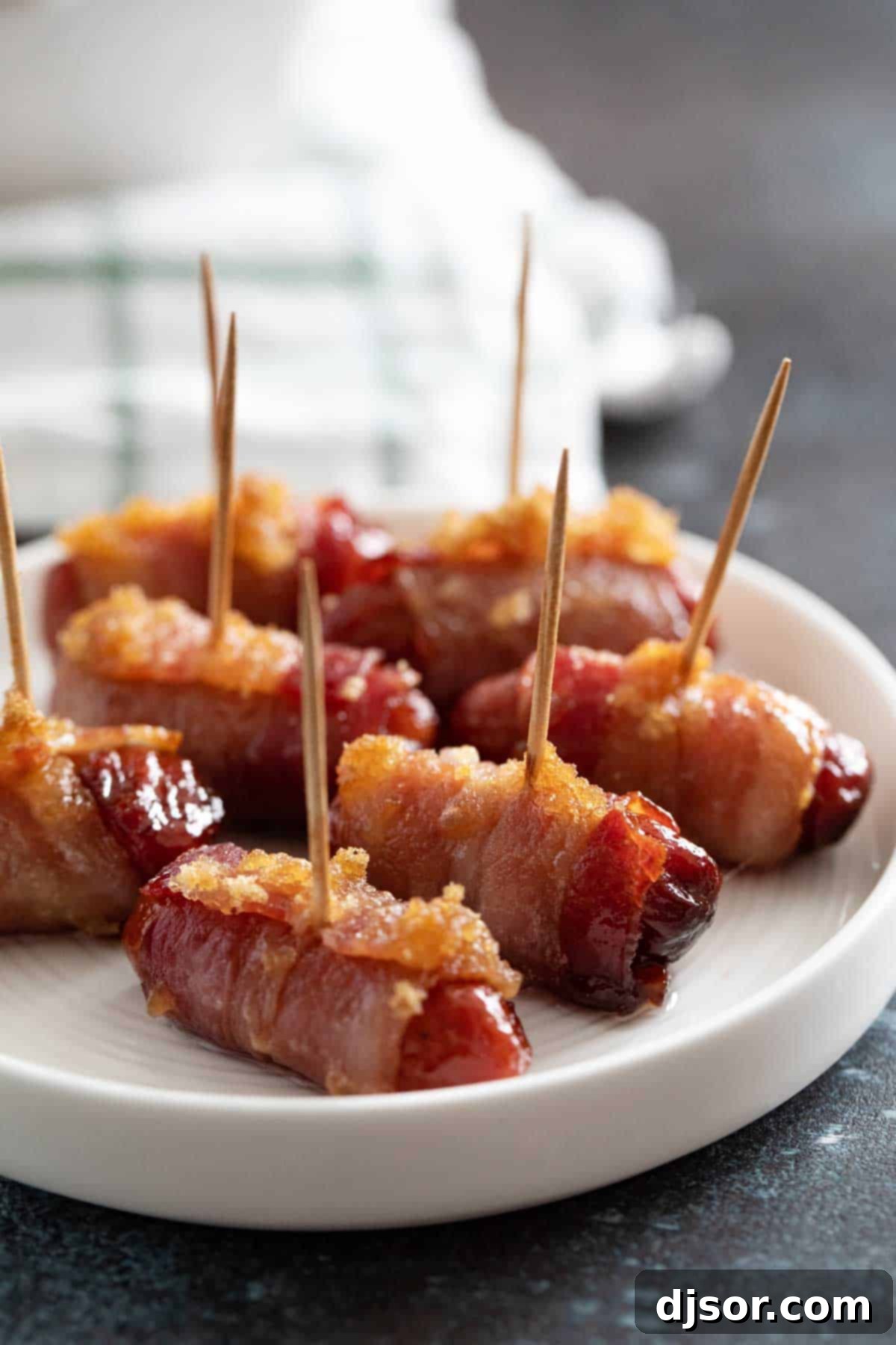 A plate filled with golden brown Bacon Wrapped Smokies, secured with toothpicks, ready to be served as a party appetizer.