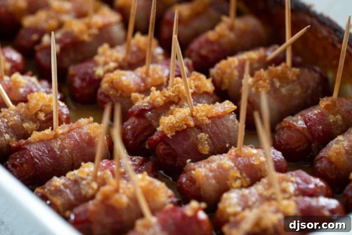 Bacon wrapped smokies covered with brown sugar, arranged neatly in a glass baking dish, ready for the oven.