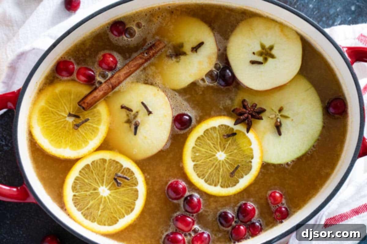 Perfect for winter celebrations or for warming up on a cold night, this hot Wassail Recipe is filled with spices and sweet juice flavors. It’s sweet and spicy and so warm and comforting! Pot filled with hot wassail topped with fruit slices, spices, and cranberries.