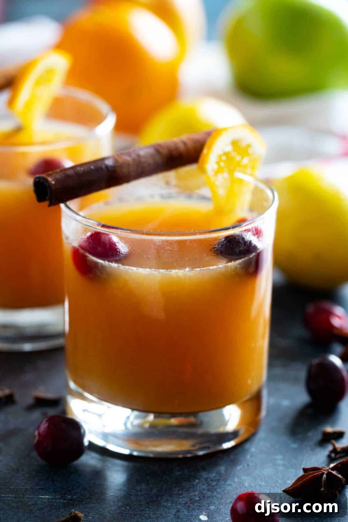 Glass filled with wassail and topped with orange slices and cranberries.