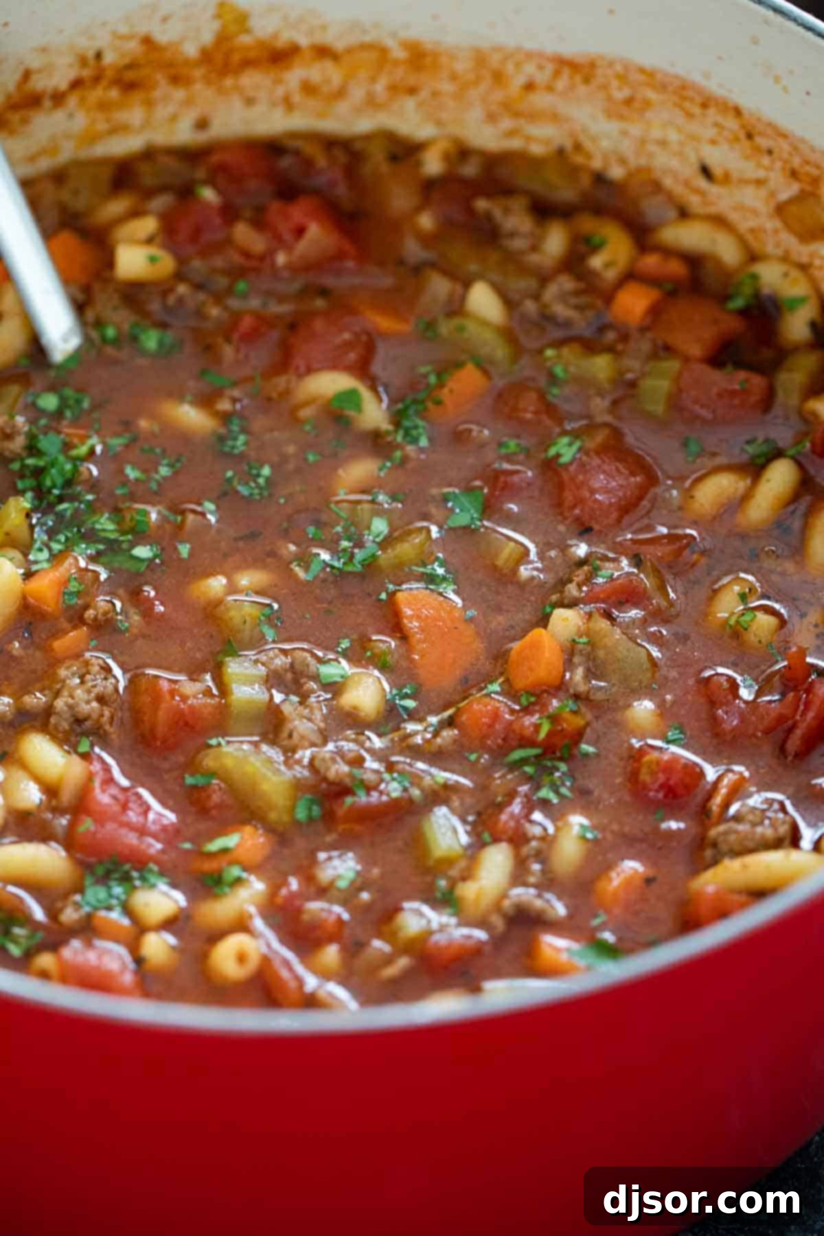 A large pot brimming with rich Hamburger Soup, garnished with a sprinkle of fresh parsley, showcasing its vibrant colors and inviting texture.