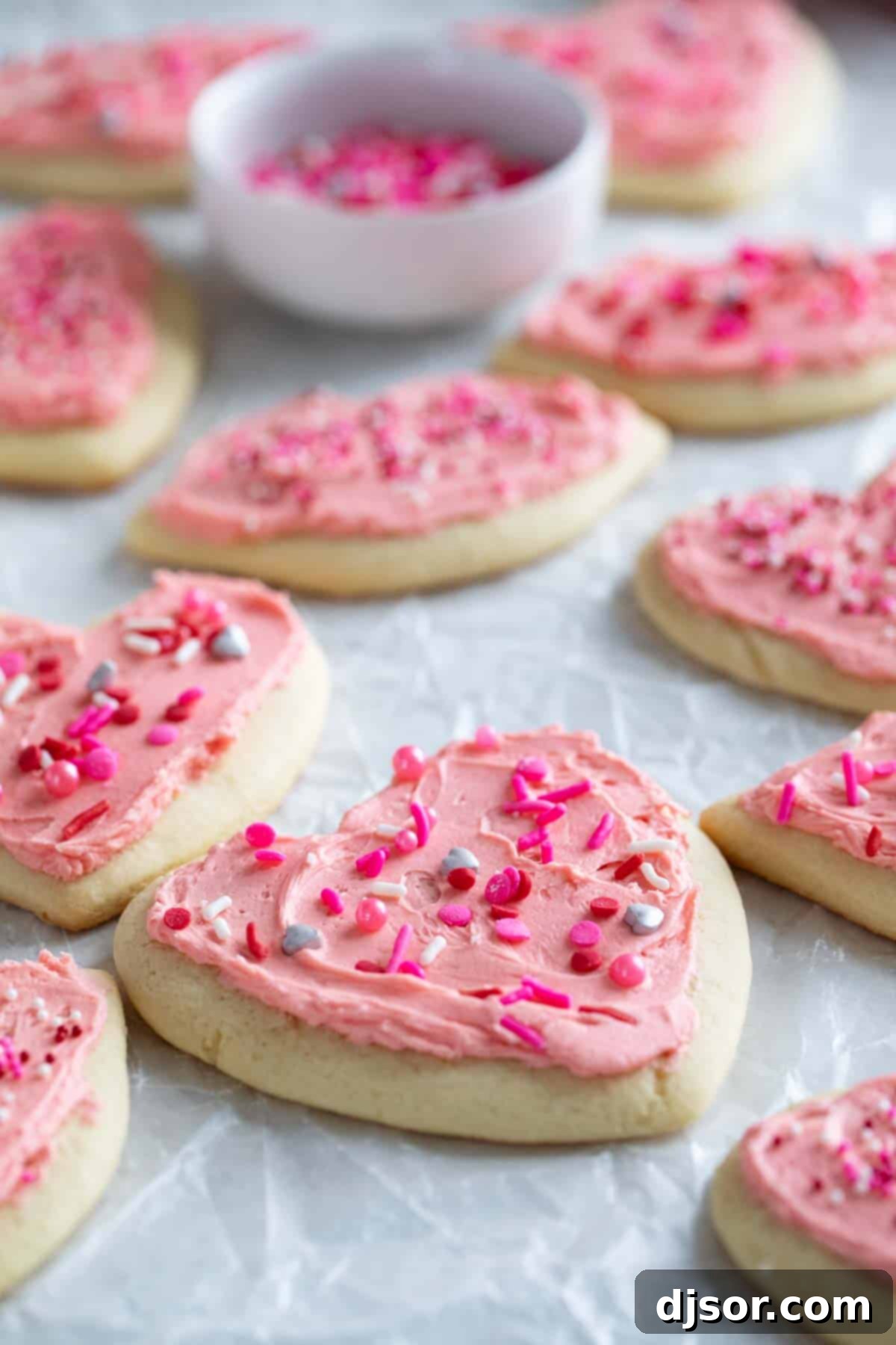 Pretty in pink, these Valentine's Day Sugar Cookies start with an easy sugar cookie recipe that is topped with the perfect pink buttercream and lots of holiday sprinkles. Shaped Valentine's day sugar cookies with pink buttercream frosting.