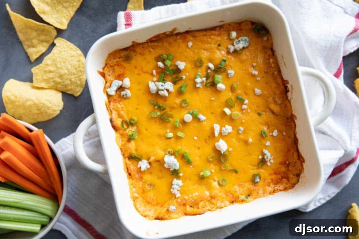 Buffalo Chicken Dip in a square white dish. A classic game day appetizer, this Buffalo Chicken Dip is so popular for a reason! Filled with all of your favorite buffalo chicken flavors, this dip is super easy to make and always disappears.