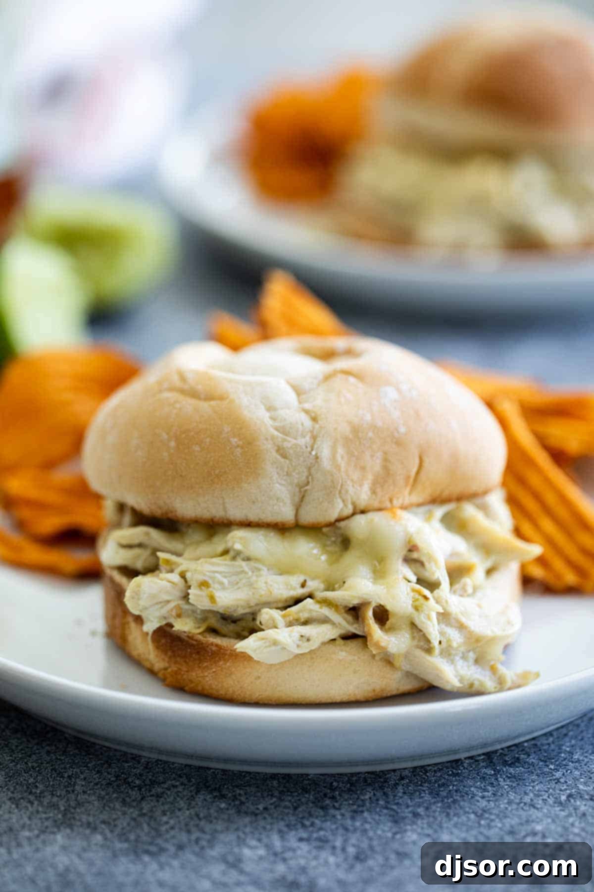 A plate of Suizas Style Pulled Chicken Sandwiches with a vibrant, creamy sauce and melted cheese