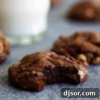 These soft Chocolate Peanut Butter Cookies are deep chocolate cookies filled with peanut butter cups and peanut butter chips. These cookies are made for chocolate and peanut butter lovers! Close-up of a Chocolate Peanut Butter Cookie with its fudgy center