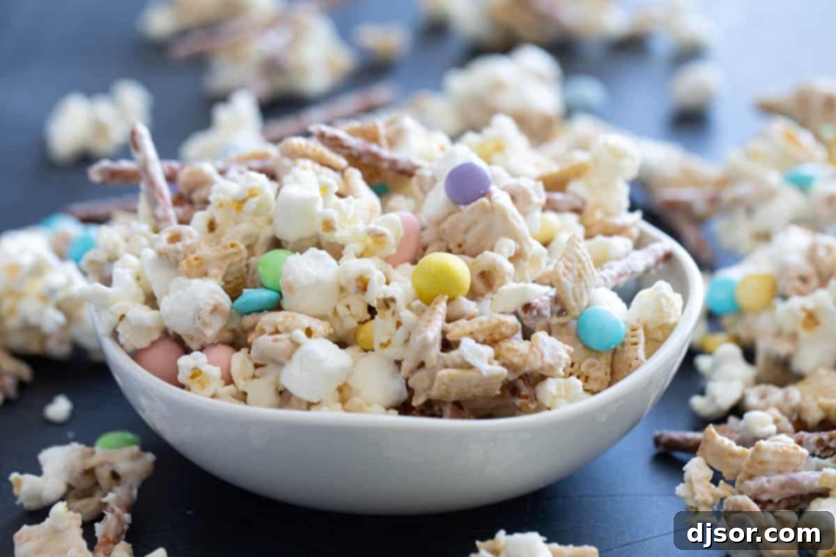 Bowl filled with Bunny Bait - cereal, pretzels, marshmallows, popcorn, and candy in white chocolate.