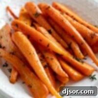 Oven roasted carrots topped with fresh thyme leaves, presented in a rustic white serving dish.