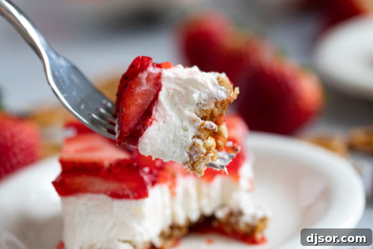 Sweet and salty, this Strawberry Pretzel Salad is as pretty as it is delicious. Serve it as a side dish or a dessert - either way, it’s always a hit! Bite of strawberry pretzel salad on a fork, showing its delicious layers.