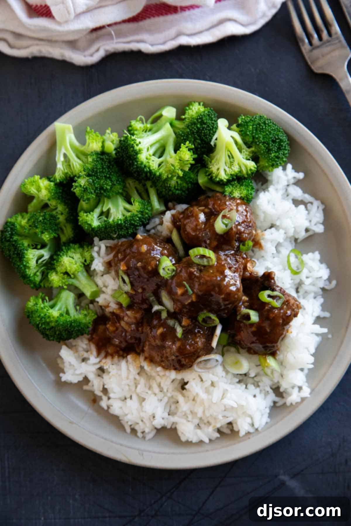 A stack of delicious Asian Meatballs served over rice, garnished with green onions.