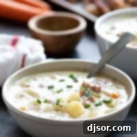 Bowl of ham and potato soup with a spoon in it.