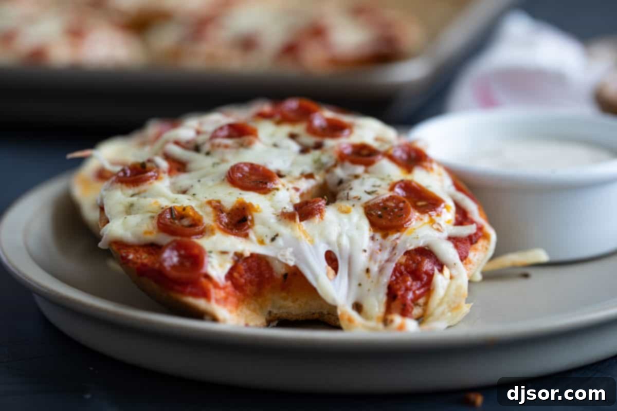 The Ultimate Bagel Pizza 7 A pizza bagel with a bite taken out of it, showing the melted cheese and pepperoni, emphasizing its deliciousness.