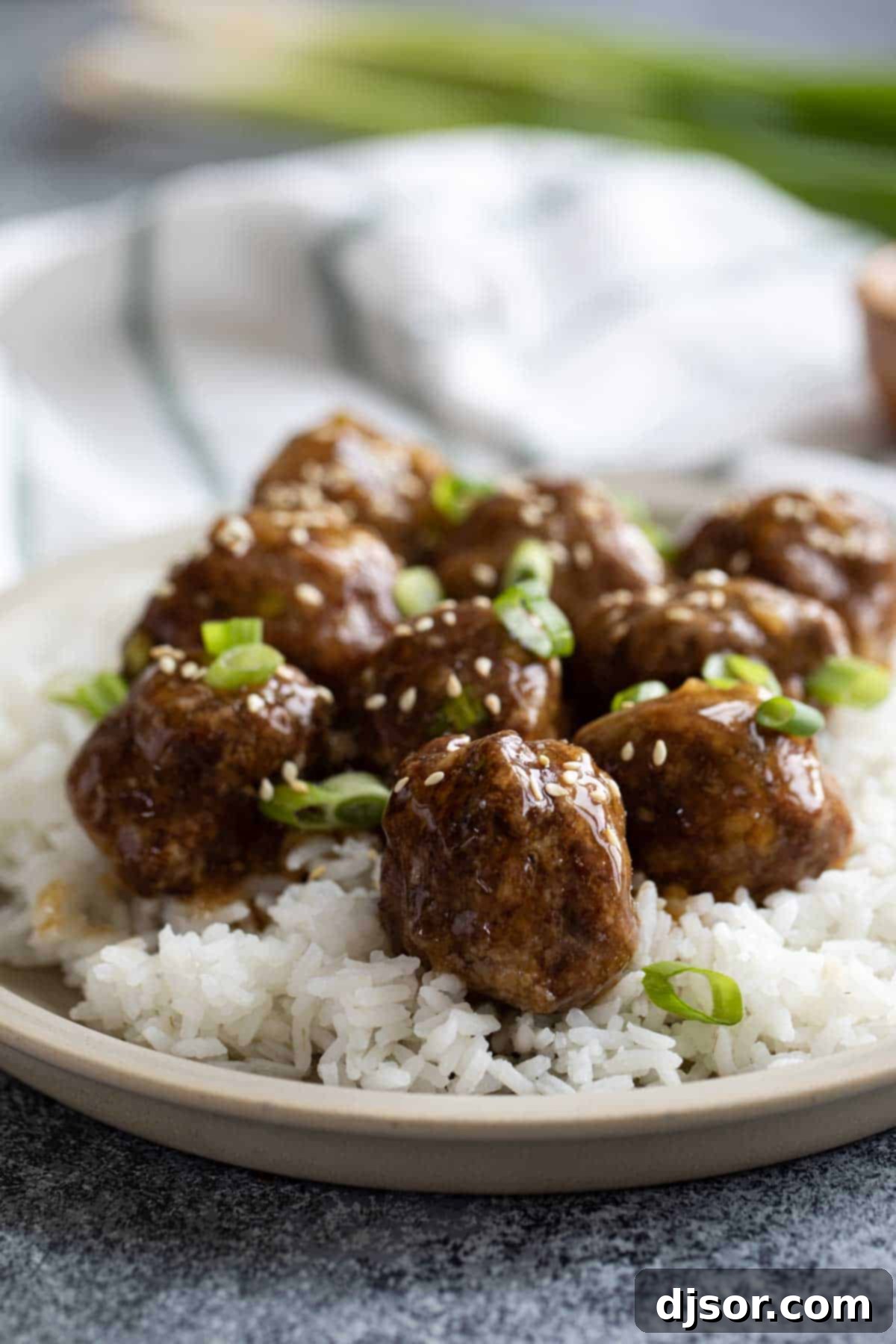 These Teriyaki Meatballs are made with a delicious homemade teriyaki sauce that is super easy and fast. The meatballs are juicy and flavorful, and the sauce is sweet, tangy, and savory. This recipe is perfect for a quick and easy weeknight dinner, or for a party appetizer. Teriyaki Meatballs and rice topped with green onions and sesame seeds.