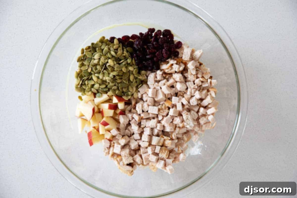 Essential ingredients for your next Honey Mustard Turkey Salad Sandwich. A vibrant selection of ingredients laid out, including mayonnaise, Dijon mustard, honey, cooked turkey, diced apples, dried cranberries, and pumpkin seeds, ready for making the Turkey Salad Sandwich.