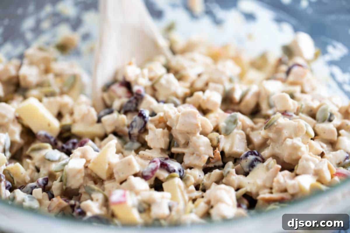 Freshly mixed Honey Mustard Turkey Salad, vibrant and ready. A large glass bowl filled with the freshly mixed Honey Mustard Turkey Salad, showing the blend of turkey, apples, cranberries, and pumpkin seeds, ready to be served.