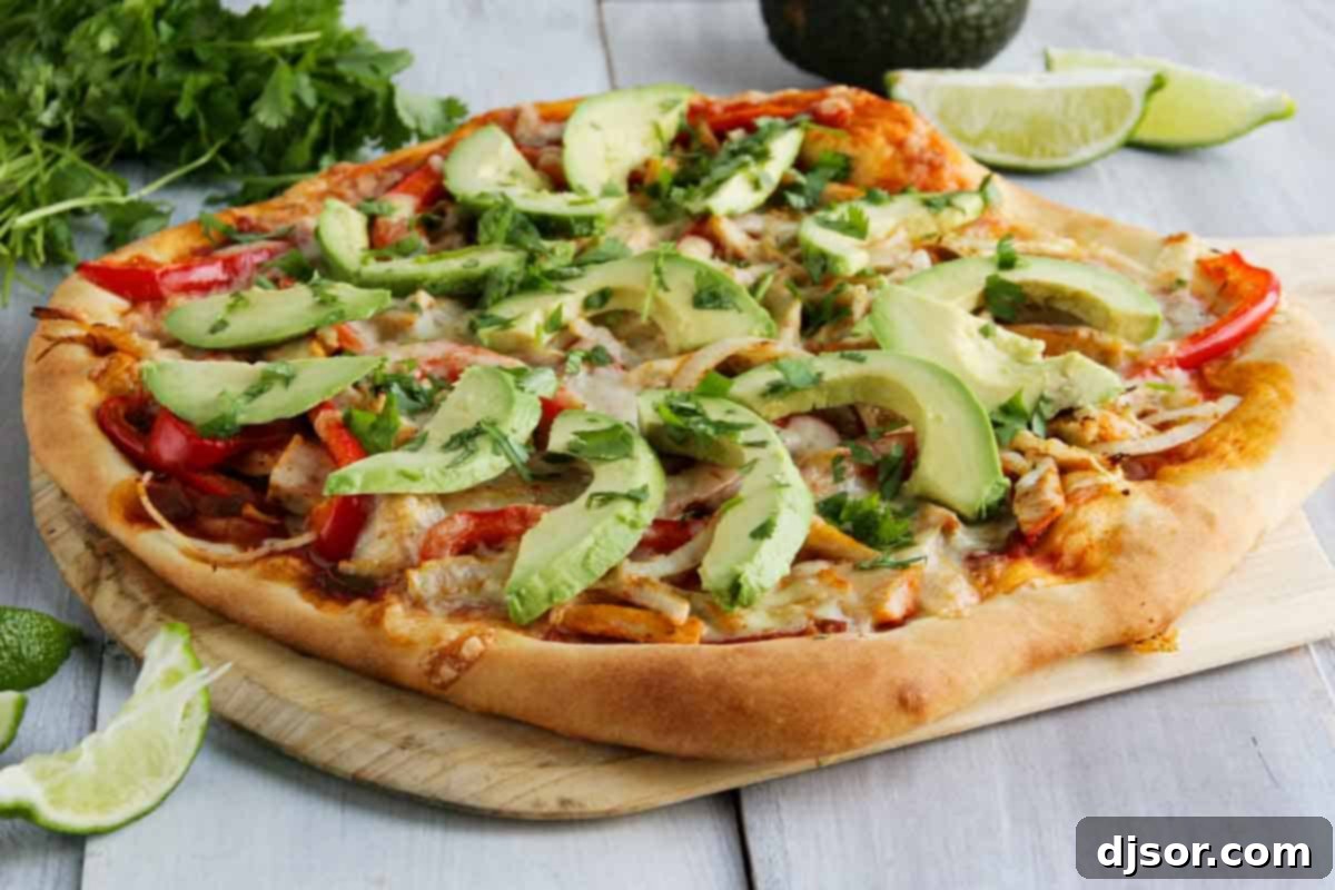 whole turkey fajita pizza topped with avocados and cilantro, ready to be sliced